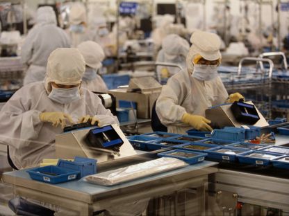 عاملات يرتدين كمامات واقية أثناء عملهن في منشأة لتصنيع الأجهزة الإلكترونية - المصدر: غيتي إيمجز