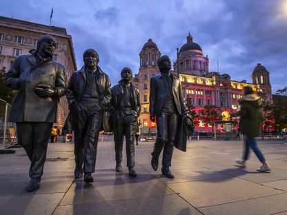 إحدى المشاة تسير إلى جانب تماثيل لأعضاء فرقة \"البيتلز\" في ساحة \"بيير هيد\"، مدينة ليفربول، المملكة المتحدة - المصدر: بلومبرغ
