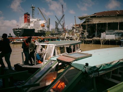 رجال يخرجون من قارب صغير يرسو في ميناء غيانا - المصدر: بلومبرغ