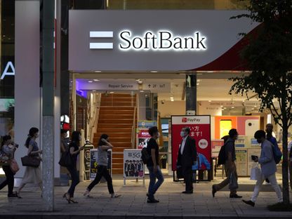 مشاة يرتدون أقنعة واقية أمام مقر \"سوفت بنك غروب\" في طوكيو، اليابان - المصدر: بلومبرغ