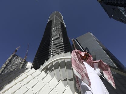 رجل يعبر من أمام برج في مركز الملك عبدالله المالي في العاصمة السعودية الرياض - المصدر: بلومبرغ