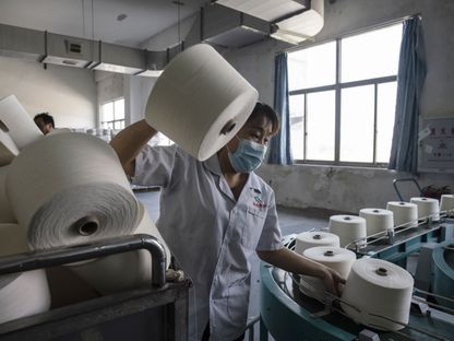 عامل يتعامل مع بكرات خيوط على خط إنتاج في مصنع Fujian Strait Textile Technology . في بوتيان ، مقاطعة فوجيان ، الصين  - المصدر: بلومبرغ