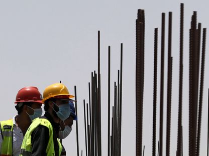 عمال يرتدون كمامات واقية يقفون إلى جانب قضبان من الحديد في مبنى قيد الإنشاء في العاصمة الإدارية الجديدة، شرق القاهرة. مصر - المصدر: رويترز