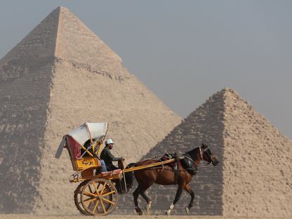 سائح يركب عربة يجرها حصان أمام هضبة الأهرامات في الجيزة - المصدر: بلومبرغ