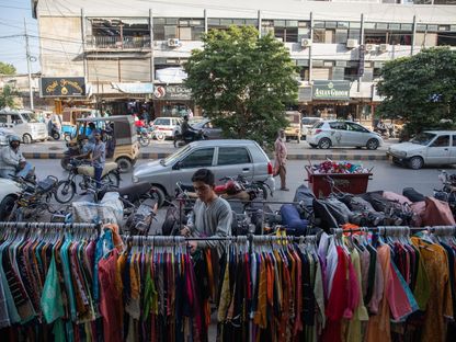 بائع يرتب معروضاته من الملابس للبيع في أحد الأسواق المفتوحة في كراتشي، باكستان. - المصدر: بلومبرغ