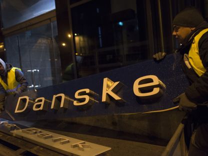 عمال يزيلون لافتات مصرف \" دانسكي بنك\" ويحملونها إلى مقطورة من فرعه السابق في تالين، إستونيا  - المصدر: بلومبرغ