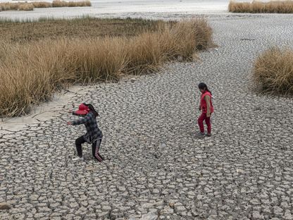 طفلتان تسيران في أرض موحلة ببحيرة تيتيكاكا التي ضربها الجفاف في هوارينا، بوليفيا، يوم الأربعاء، 1 نوفمبر 2023 - المصدر: بلومبرغ