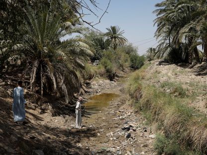 فلاحون يمشون على مجرى نهر جاف في ضواحي النجف، العراق. 23 يونيو 2023  - المصدر: رويترز