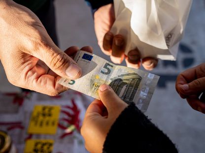عميل يسلم ورقة نقدية بقيمة خمسة يورو في كشك بأحد شوارع بريشيا، إيطاليا - المصدر: بلومبرغ