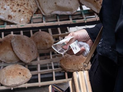 شخص يشتري مجموعة من أرغفة الخبز المصري - المصدر: بلومبرغ