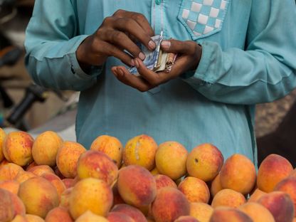 بائع الخوخ يعد أوراق نقدية باكستانية بسوق محلي في كراتشي في باكستان - المصدر: بلومبرغ