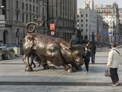 سياح يلتقطون الصور بجانب مجسم الثور المهاجم في شنغهاي - المصدر: بلومبرغ