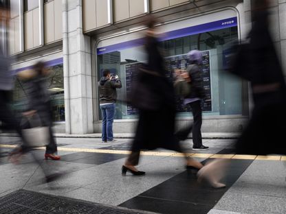 أحد المشاة يلتقط صورة للوحة أسهم إلكترونية خارج شركة للأوراق المالية في طوكيو، اليابان، يوم الجمعة، 1 مارس 2019 - المصدر: بلومبرغ