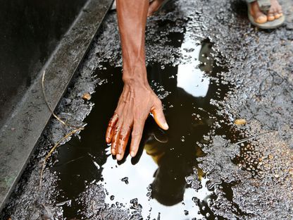 رجل يلمس النفط المتسرب على الأرض من محطة النفط المهجورة، نيجيريا - المصدر: بلومبرغ