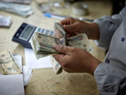 شخص في محل صرافة يعدّ أوراقاً نقدية من فئة 100 جنيه مصري - المصدر: بلومبرغ