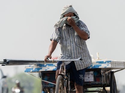 عامل ينقل مستلزمات بناء على دراجته في أحد الولايات الهندية - المصدر: بلومبرغ