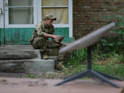 جندي أوكراني ينظر إلى هاتف ويبدو أمامه هوائي استقبال من شركة \"ستارلينك\" - Getty Images