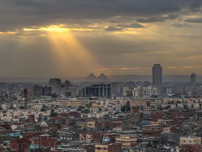 صورة تظهر مباني سكنية وتجارية في مدينة القاهرة، وفي الخلفية أهرامات الجيزة، مصر. - المصدر: بلومبرغ