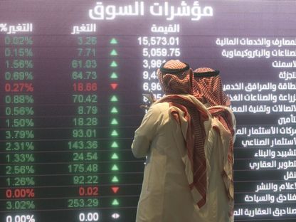 زائران يراقبان حركة الأسهم المعروضة على شاشة إلكترونية كبيرة داخل السوق المالية السعودية في الرياض - المصدر: بلومبرغ