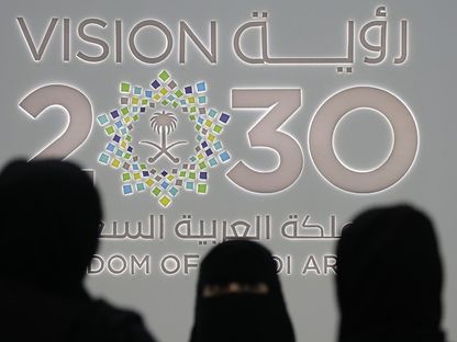 سيدات يقفن أمام شعار رؤية 2030 خلل مؤتمر بالعاصمة السعودية الرياض (أرشيفية) - الشرق/بلومبرغ