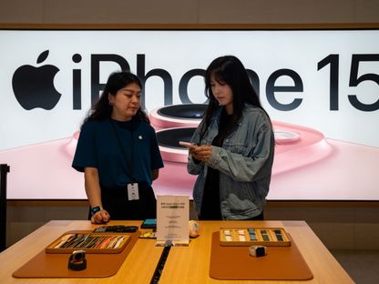 موظفة تساعد أحد العملاء في متجر \"أبل\" خلال اليوم الأول من بيع \"أيفون 15\" في بكين. - المصدر: بلومبرغ