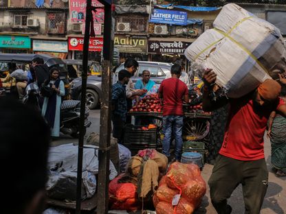 عامل يحمل بضائع في منطقة دارافي في مومباي، الهند - المصدر: بلومبرغ