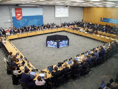 اجتماع لمجموعة العمل المالي بمشاركة ممثلين من مختلف الدول، حيث يجلس المشاركون حول طاولة مستديرة وأمامهم حواسيب وشاشات كبيرة - بلومبرغ