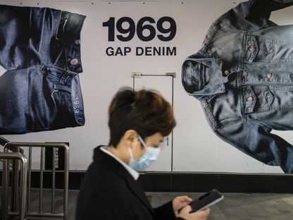 أحد المشاة يرتدي قناعاً يمر أمام متجر شركة غاب في شنغهاي ، الصين - المصدر: بلومبرغ