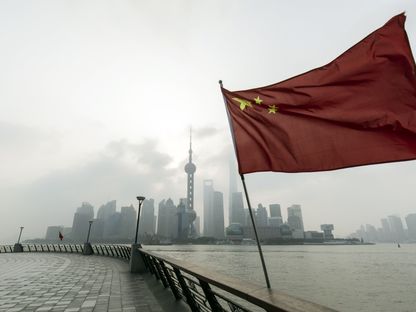 علم الصين أمام مباني في منطقة لوجياتسوي المالية ببودونغ في شنغهاي بالصين - المصدر: بلومبرغ