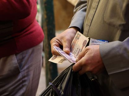 رجل يحصي مجموعة من الأوراق النقدية فئة 50 جنيهاً مصرياً - المصدر: بلومبرغ