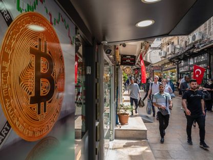 شعار العملة المشفرة \"بتكوين\" يظهر عبر نافذة مكتب صرف العملات المشفرة في اسطنبول ، تركيا  - المصدر: بلومبرغ