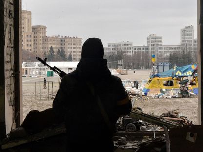 شخص مسلح ينظر نحو الميدان المركزي في مدينة خاركوف. أوكرانيا  - المصدر: غيتي إيمجز