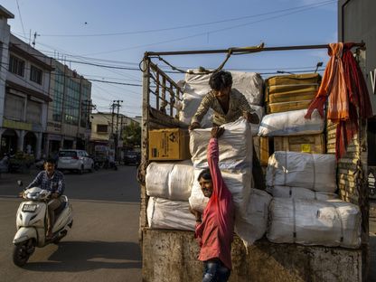 عمال يفرغون البضائع من شاحنة في منطقة السوق الرئيسية في غانديهام، الهند. - المصدر: بلومبرغ