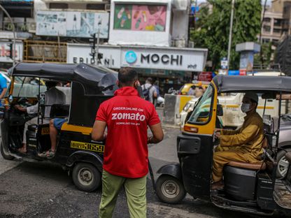موظف توصيل من شركة \"زوماتو\" يحمل طلباً إلى أحد الزبائن في مومباي، الهند، 16 يوليو، 2021. تم الاكتتاب في الطرح العام الأولي للشركة بقيمة 1.3 مليار دولار بالكامل في اليوم الأول من البيع، بعد أن فاقت طلبات الاكتتاب من قبل الصناديق الرئيسية، بما في ذلك شركة \"بلاك روك\"، العرض بأكثر من 35 مرة. - المصدر: بلومبرغ