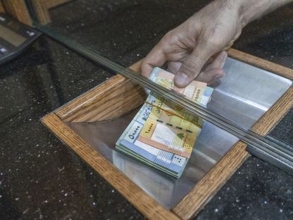 موظف يحمل رزمة من الأوراق النقدية فئة 10 آلاف و50 ألف ليرة، في أحد مكاتب الصرافة في منطقة برج حمود، في العاصمة بيروت، لبنان - المصدر: بلومبرغ