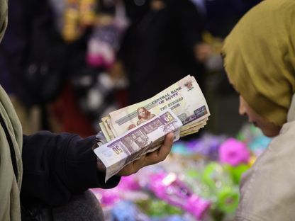 بائع مصري يمسك بيديه رزمة من الأوراق النقدية بالجنيه المصري - المصدر: بلومبرغ