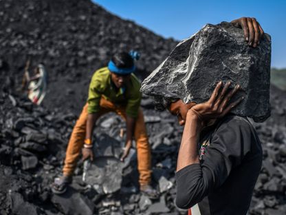عمال يحملون قطعاً من الفحم في ساحة بالقرب من منجم للفحم في سونبادرا بولاية أوتار براديش، الهند