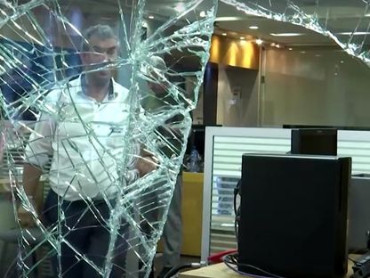 شخص يقف خلف زجاج مكسور بداخل أحد البنوك اللبنانية التي شهدت عملية اقتحام - المصدر: رويترز