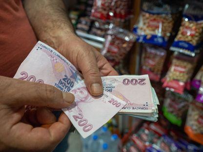 عميل يمسك عملات نقدية من فئة 200 ليرة تركية في اسطنبول، تركيا. - المصدر: بلومبرغ