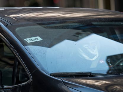 سائق يرتدي غطاء واقٍ للوجه يقود سيارة تعرض لافتات Uber Technologies في شارع كاليفورنيا في سان فرانسيسكو ، كاليفورنيا ، الولايات المتحدة  - المصدر: بلومبرغ