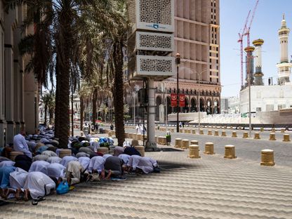 رجال يصلون في الظل في أحد الأحياء بمكة المكرمة، المملكة العربية السعودية - المصدر: بلومبرغ