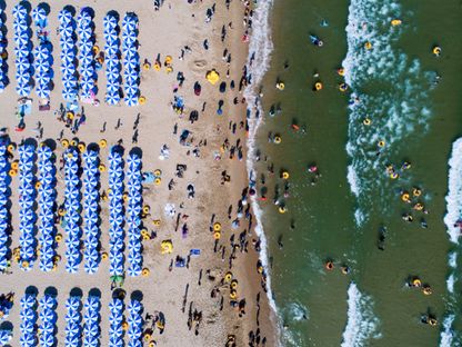 أشخاص يسبحون ويستلقون تحت أشعة الشمس على شاطئ هايونداي في بوسان، كوريا الجنوبية - المصدر: بلومبرغ
