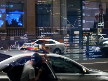 صورة السيارات وهي منعكسة على نافذة متجر يعرض بيانات الأسهم في بورصة الأوراق المالية الأسترالية، سيدني، أستراليا - المصدر: بلومبرغ
