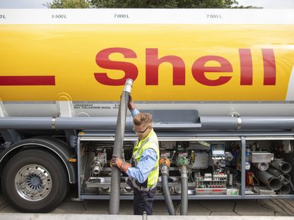 عامل يستخدم خرطوماً لضخ الوقود من شاحنة صهريجية تابعة لشركة \"شل\" بفي محطة وقود - المصدر: بلومبرغ