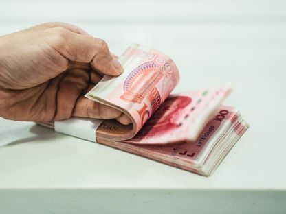 شخص ممسك برزمة أوراق نقدية فئة مئة يوان صيني - المصدر: بلومبرغ