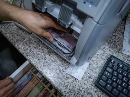 موظف يعد أوراق نقدية بالليرة التركية بآلة عد النقود - المصدر: بلومبرغ