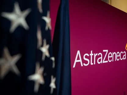 لافتة شركة 'أسترازينيكا' البريطانية بجوار العلم الأميركي قبل حفل توقيع اتفاق خفض أسعار أدويتها في أميركا، البيت الأبيض، واشنطن، الولايات المتحدة - بلومبرغ