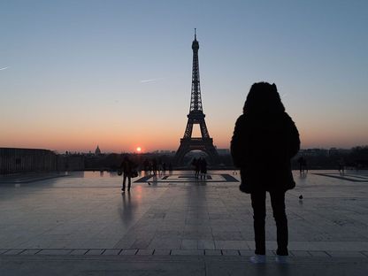 سائح يقف أمام برج إيفل عند شروق الشمس، باريس، فرنسا - المصدر: بلومبرغ