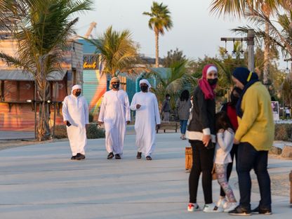 مشاة يرتدون أقنعة واقية يسيرون في مشروع \"لامير\" في دبي - المصدر: بلومبرغ