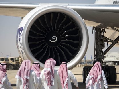 زوار يسيرون بجوار محرك نفاث لطائرة بوينغ طراز \"777-368\"، تديرها الخطوط الجوية العربية السعودية، في مطار الثمامة في الرياض، المملكة العربية السعودية - المصدر: بلومبرغ